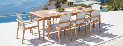 Wooden dining set beside ocean pool.