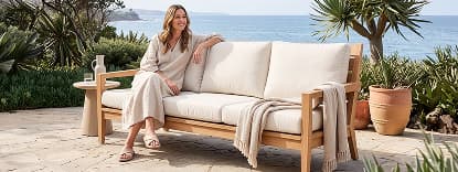 Woman relaxing on cushioned wooden sofa.