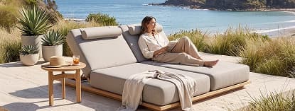 Woman reading on double outdoor lounger.
