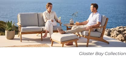 Couple lounging on teak patio set. Image Text: Gloster Bay Collection