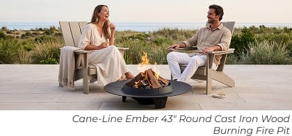 Couple laughing near round fire pit. Image Text: Cane-Line Ember 43" Round Cast Iron Wood Burning Fire Pit