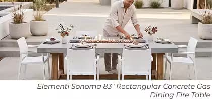 Elementi Sonoma rectangular dining fire table set with place settings and a man arranging the table.