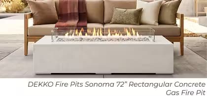 White DEKKO Sonoma rectangular gas fire pit with glass wind guard in front of a cushioned outdoor sofa.