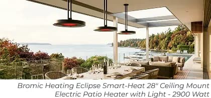 Three hanging patio heaters above a coastal outdoor dining table and lounge area.