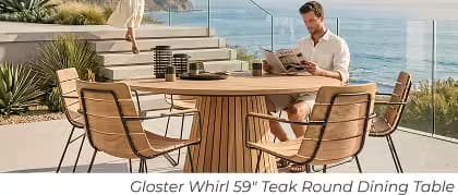 Man reading at a round teak outdoor dining table with wood and metal chairs overlooking the ocean.