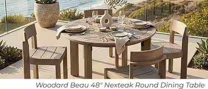 Round wood outdoor dining table with four chairs and neutral place settings overlooking the coast.